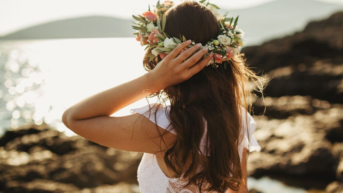 Frau mit Blumenkranz auf dem Kopf, die auf einen See blickt
