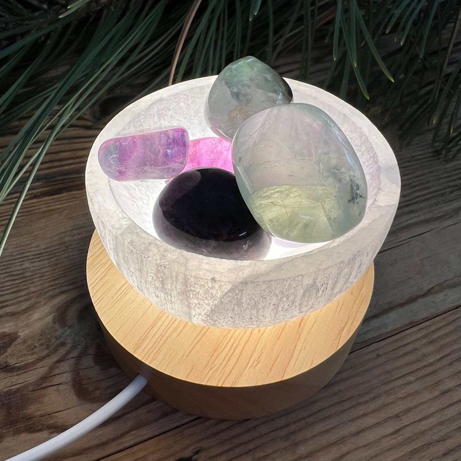 Selenitschale mit Fluorit-Trommelsteinen auf Lichtsockel